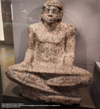 89_1-Dynasty-5,-granite,-Saqqara,-Ancient-Egypt,-History-Pharaohs,-Grand-Egyptian-Museum,-Unnamed-scribe-statue-reading-text-in-hieroglyphs-and-cursive-written-on-a-papyrus-roll